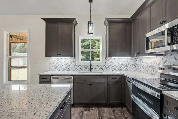 a kitchen with stainless steel appliances granite countertop a sink stove and microwave