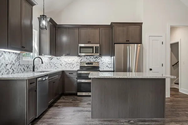 a kitchen with kitchen island granite countertop a sink stove and refrigerator with wooden floor