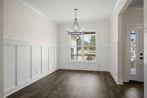 an empty room with wooden floor exposed radiator and windows