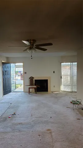 an empty room with windows and ceiling fan