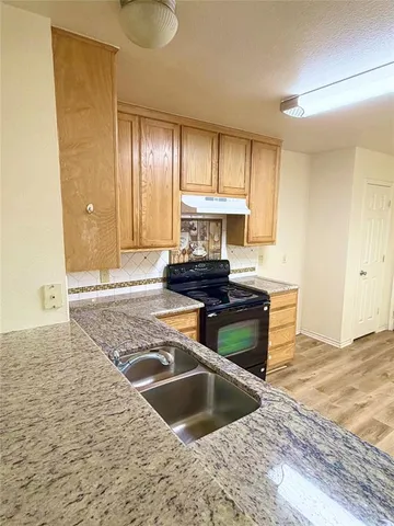 a kitchen with granite countertop a sink and a stove top oven