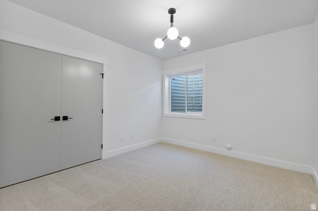 710 East Mountain Road North Ogden, UT 84414 - Photo 28 of 36 Unfurnished bedroom featuring a closet, light colored carpet, and a chandelier