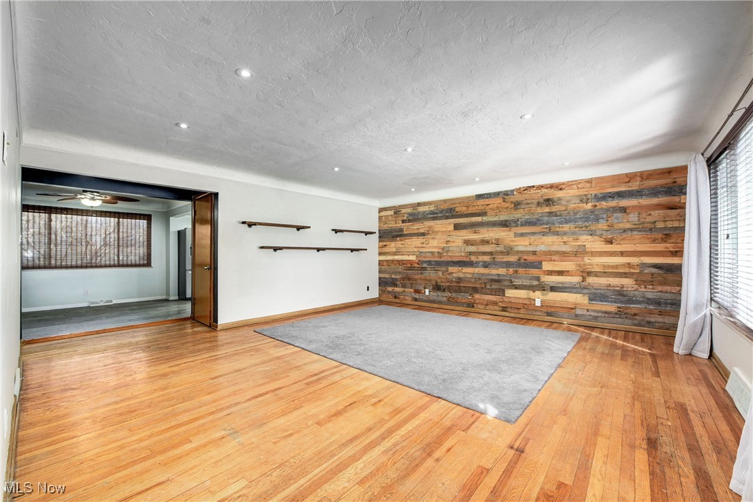 11518 Prospect Road Strongsville, OH 44149 - Photo 9 of 46 Unfurnished living room featuring wood walls, baseboards, a textured ceiling, and wood finished floors