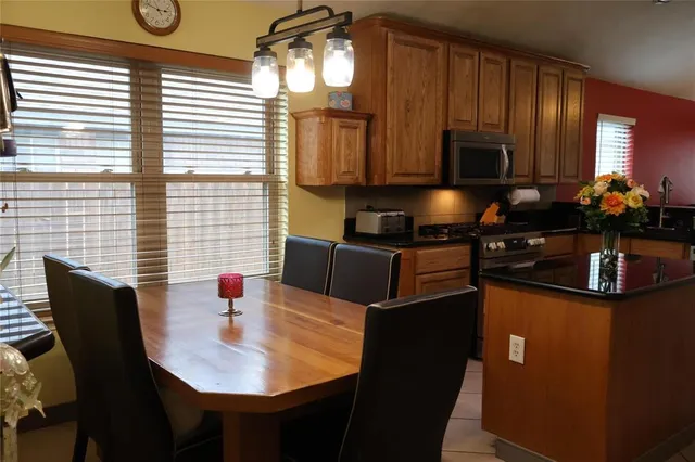a kitchen with stainless steel appliances granite countertop a sink a microwave cabinets and a dining table
