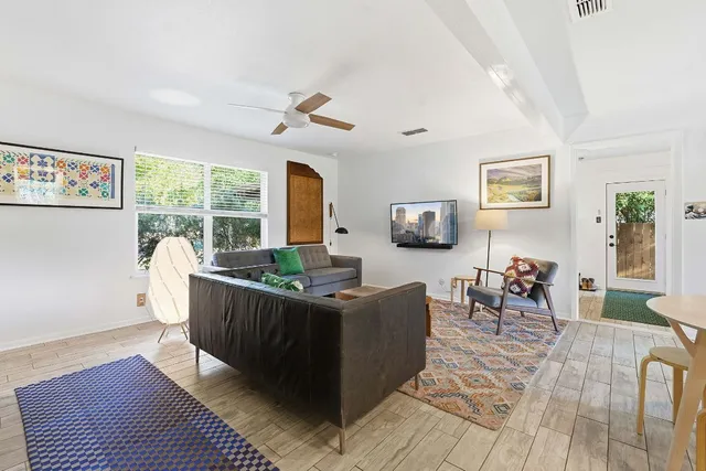 a living room with furniture a large window and wooden floor