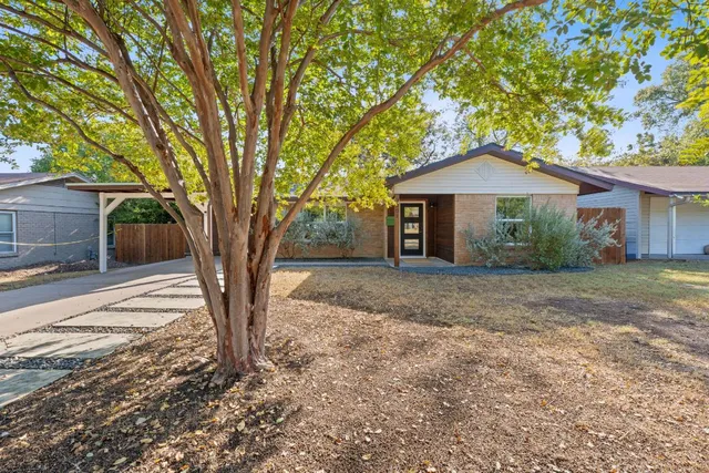a front view of a house with yard and tree