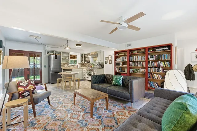a living room with furniture kitchen view and a large window