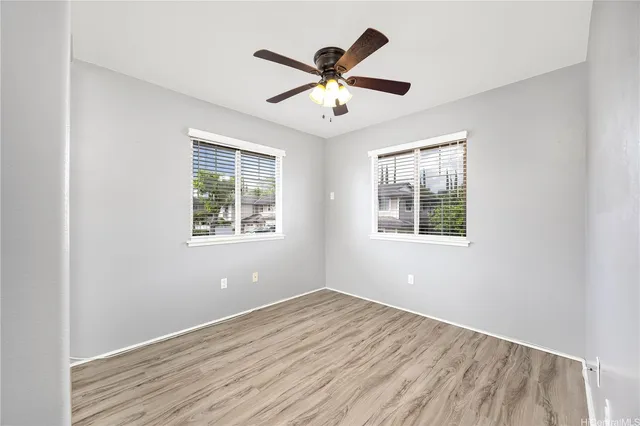 an empty room with windows and ceiling fan