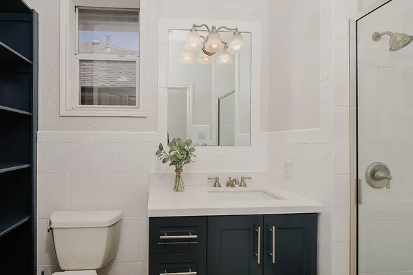 a bathroom with a granite countertop sink a toilet and with mirror