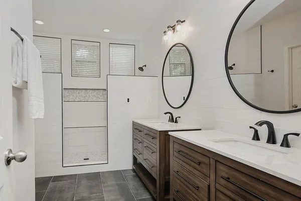 a bathroom with a double vanity sink mirror and bathtub