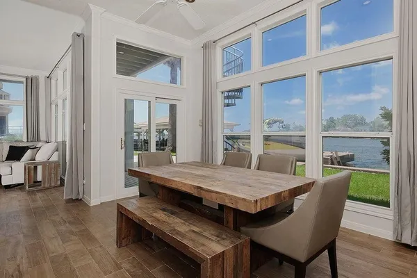 a dining room with wooden floor and large windows
