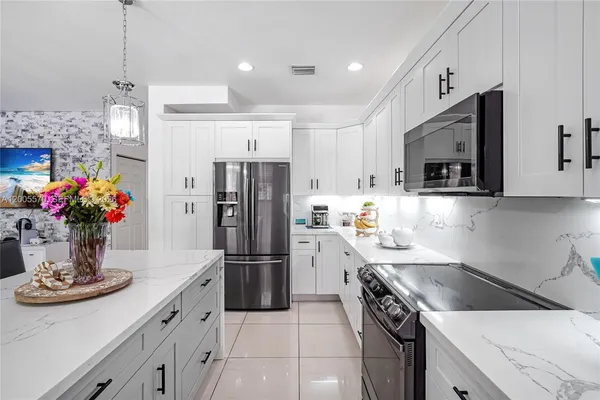 a kitchen with a sink dishwasher and white cabinets with wooden floor