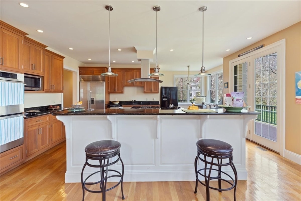 8 Middleby Road Lexington, MA 02421 - Photo 10 of 42 a kitchen with stainless steel appliances granite countertop a stove top oven a sink a dining table and chairs with wooden floor