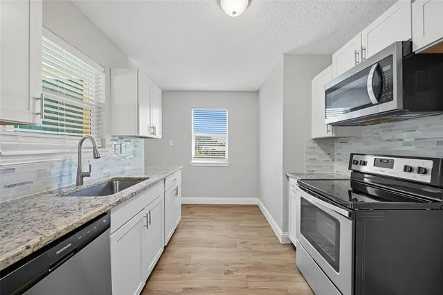 a kitchen with stainless steel appliances granite countertop a sink stove and microwave