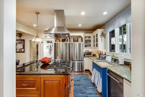 a kitchen with stainless steel appliances granite countertop a stove a sink dishwasher a dining table and chairs with wooden floor