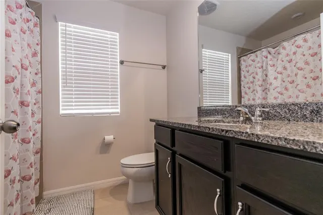 a bathroom with a granite countertop sink toilet and mirror