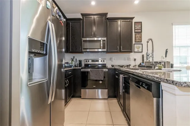 a kitchen with stainless steel appliances granite countertop a refrigerator and a stove top oven