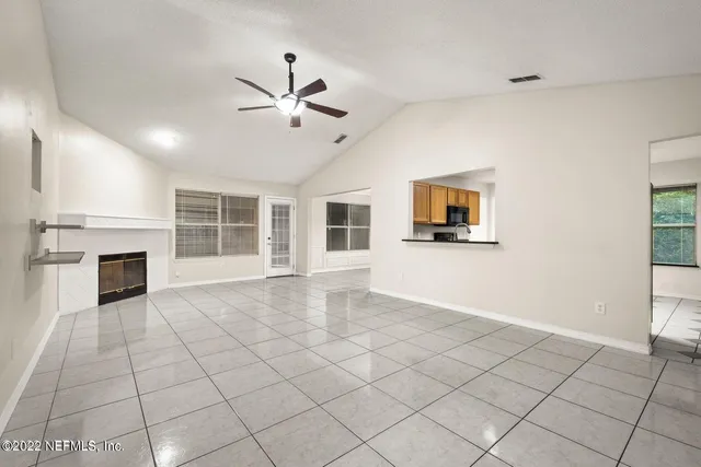 a view of a livingroom with a fireplace a ceiling fan and windows