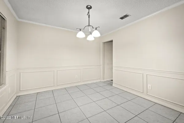 a view of an empty room with a chandelier fan