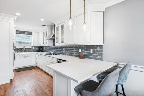 a kitchen with a sink a stove and white cabinets