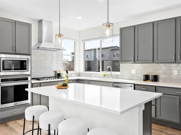 a kitchen with stainless steel appliances kitchen island granite countertop a stove a sink a refrigerator and white cabinets with wooden floor