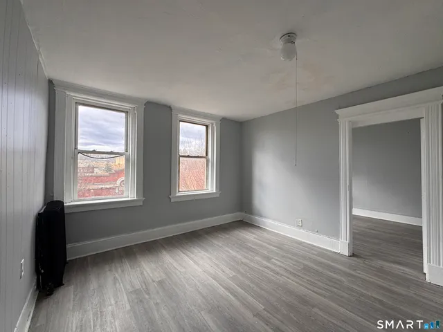 an empty room with wooden floor and windows