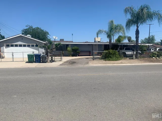 a view of a house with a yard and palm trees