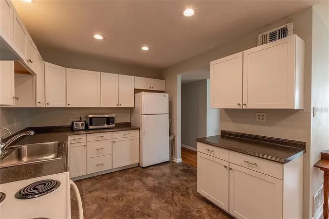a kitchen with white cabinets and refrigerator