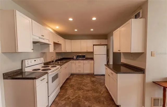 a kitchen with granite countertop a sink stove and refrigerator