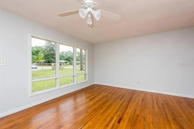 a view of an empty room with wooden floor and a window