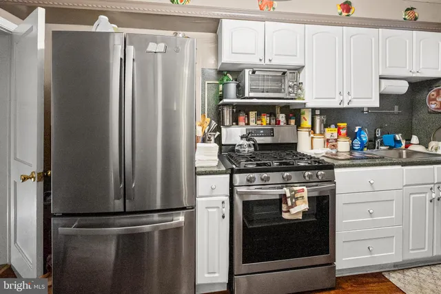 a kitchen with stainless steel appliances white cabinets and a refrigerator