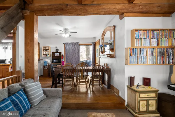 a living room with furniture a bookshelf and kitchen view
