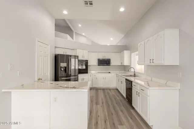 a large kitchen with stainless steel appliances kitchen island granite countertop a stove and a sink