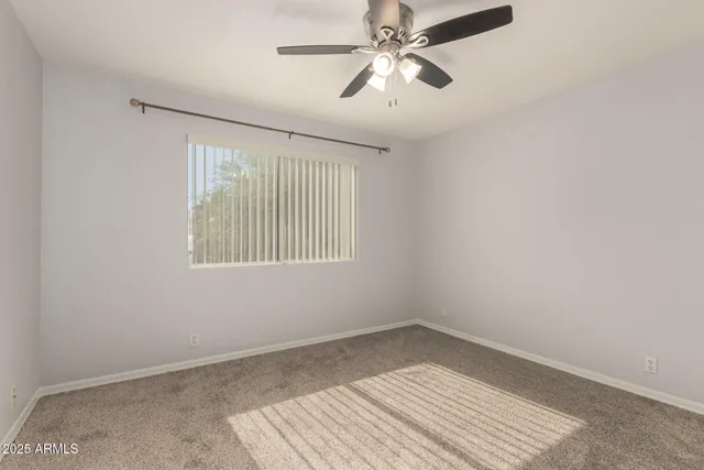 an empty room with a window and a ceiling fan