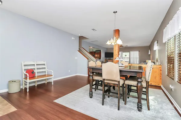 a dining room with wooden floor a chandelier a wooden table and chairs