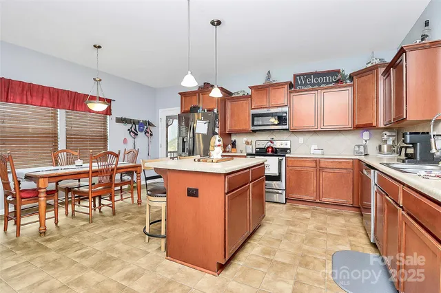 a kitchen with stainless steel appliances granite countertop a stove top oven a sink a dining table and chairs