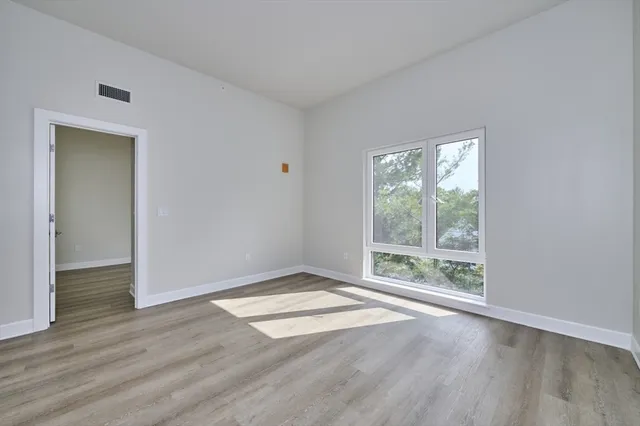 an empty room with wooden floor and windows