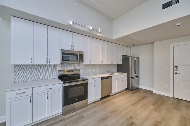 a kitchen with granite countertop white cabinets and stainless steel appliances