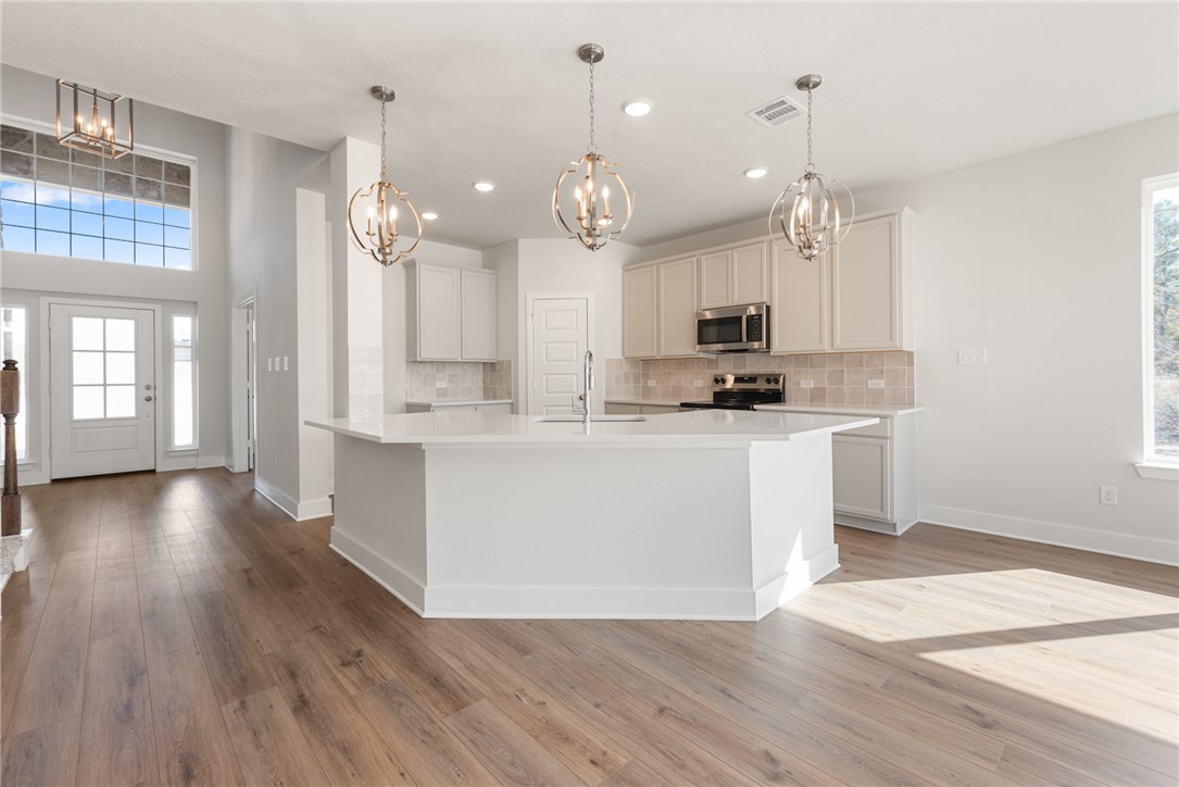 8452 Muir Wood Loop Anderson, TX 77830 - Photo 13 of 48 a large kitchen with stainless steel appliances kitchen island granite countertop a stove a sink a refrigerator and a wooden floor