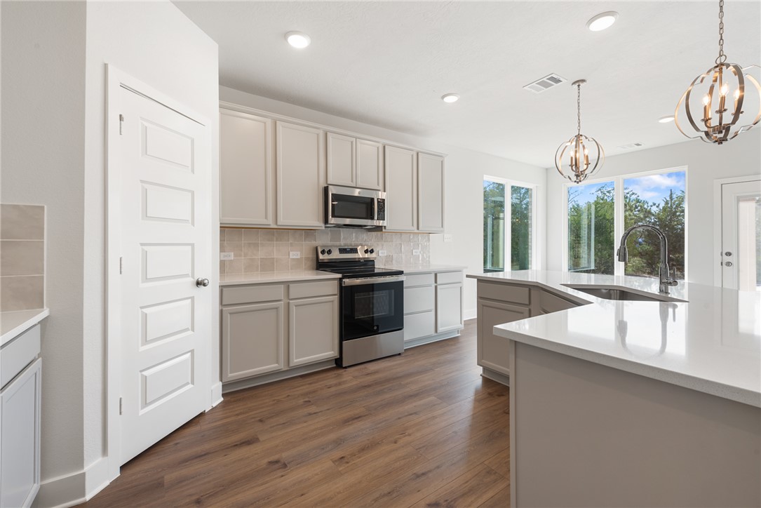8452 Muir Wood Loop Anderson, TX 77830 - Photo 18 of 48 a kitchen with stainless steel appliances granite countertop a refrigerator a stove cabinets and wooden floor