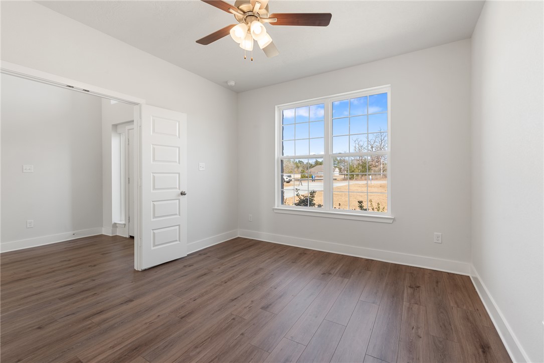 8452 Muir Wood Loop Anderson, TX 77830 - Photo 5 of 48 an empty room with wooden floor chandelier fan and windows