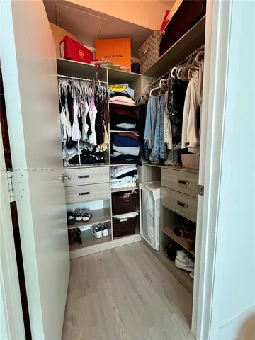 a view of walk in closet with clothes and shoes