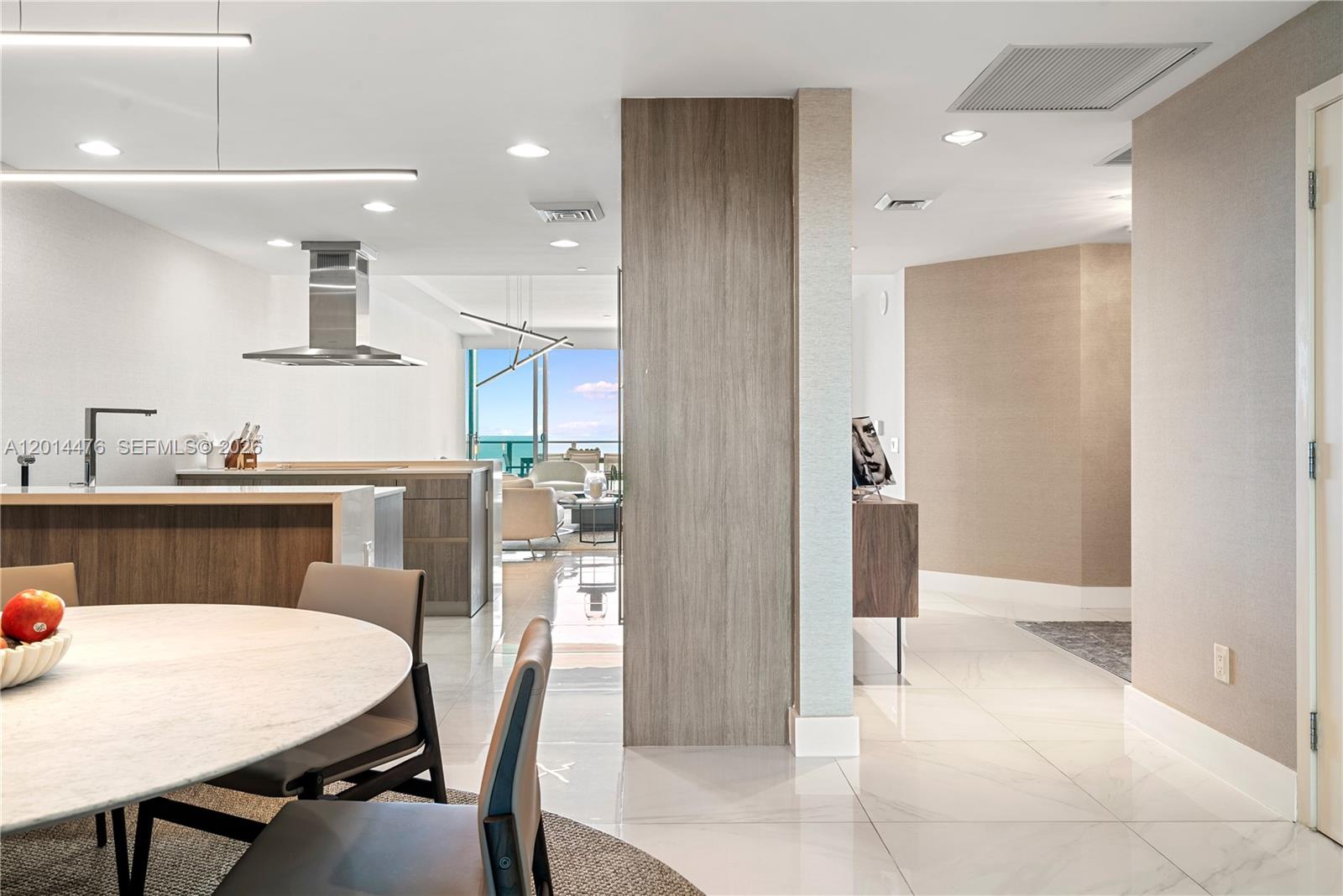 360 Ocean Drive, Unit 1106S Key Biscayne, FL 33149 - Photo 13 of 67 Dining / Open Layout – This view highlights the home’s open circulation between the dining area, kitchen, foyer, and living space. Glossy flooring, warm wood accents, and distant water views create a bright, cohesive interior.