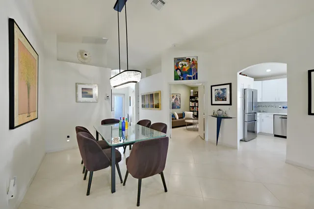 a kitchen with stainless steel appliances kitchen island granite countertop a stove top oven a sink a dining table and chairs with white cabinets