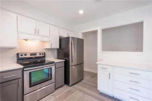 a kitchen with cabinets stainless steel appliances and wooden floor