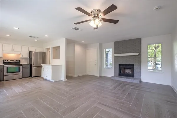 a view of a livingroom with a fireplace a ceiling fan and windows