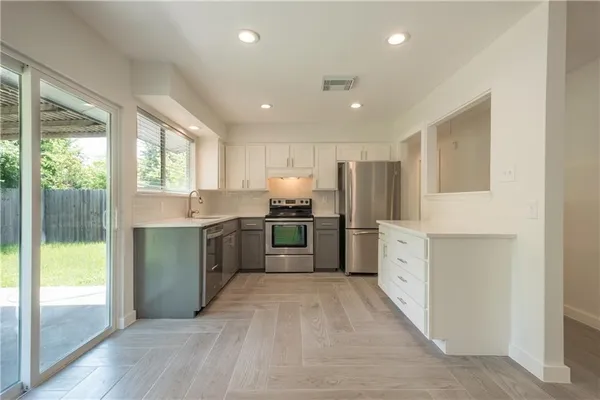 a large kitchen with a large counter top a sink stainless steel appliances and cabinets
