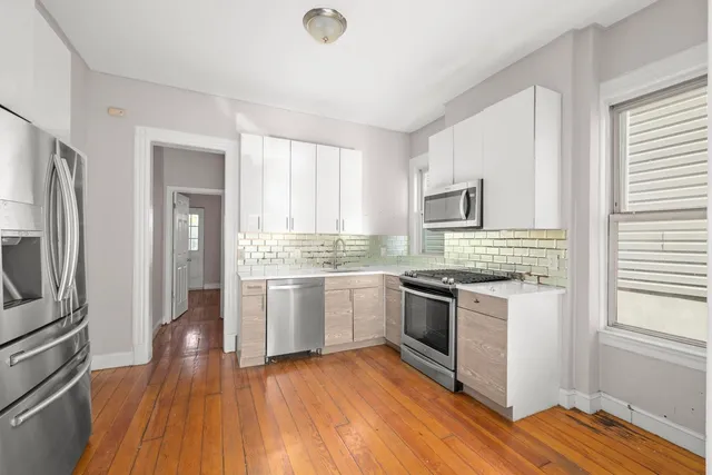 a kitchen with a sink wooden floor and stainless steel appliances