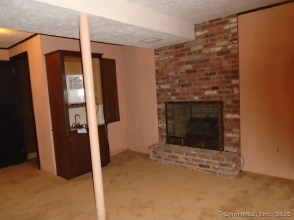 a view of an empty room with wooden floor and a fireplace