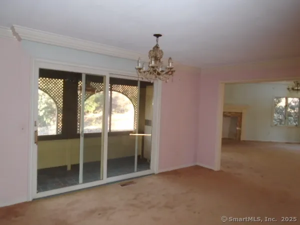 an empty room that has a large window and chandelier